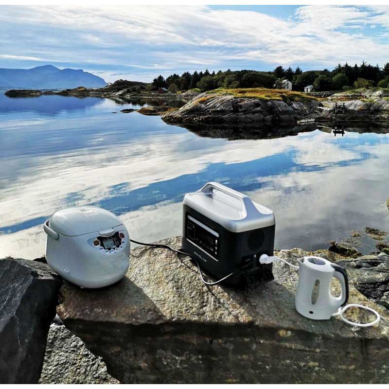 Aeon Guardians G1200 power station and electronic devices on a rock by a scenic lakeside.