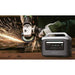 Person using an angle grinder with sparks, next to an Aeon Guardians G1200 power station on a wooden surface.