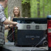 Two people using an EcoFlow Delta Pro power station device on a truck bed in a forest setting