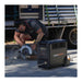 Person using a PS3600 Pro portable power station with a circular saw, with a truck in the background.